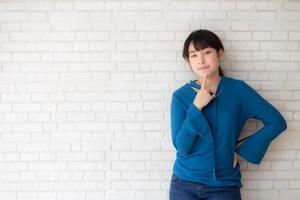 Beautiful portrait young asian woman confident thinking with cement and concrete background, girl standing expression serious or doubts with idea, lifestyle concept. photo