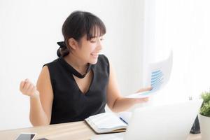 Beautiful young asian woman working laptop computer at office, businesswoman looking graph diagram analysis statistic data with excited and success, girl using notebook, business concept. photo
