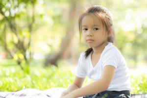 Portrait face of cute asian little girl and child happiness and fun in the park in the summer, smile and happy from asia kid and relax in the garden, lifestyle childhood concept. photo