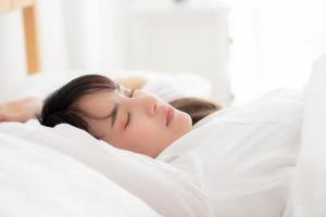 bella joven asiática durmiendo en la cama con la cabeza en la almohada cómoda y feliz. chica con relax por concepto de salud.