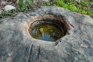 A close up shot of a round pothole on a stone filled with rain water. Uttarakhand India. photo