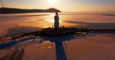 vista aérea del paisaje marino con un faro en el fondo de la puesta de sol. foto