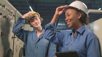 Professional female African American and White engineers partner take off hard hats after work and look at camera with happy smiles and positive expressions in an industry manufacturing factory. video