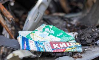 The car burned down completely. A paper map of the city of Kyiv in the interior of a destroyed car. Disaster zone. Abandoned car on the road. Ukraine, Irpen - May 12, 2022. photo