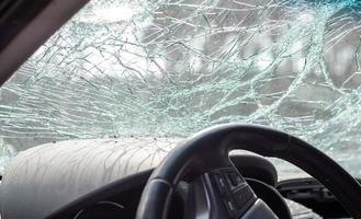 Damaged car window after an accident. Broken windshield as a result of an accident, inside view. Cabin interior details, view from the cab. Safe movement. Broken windshield. Glass crack and damage. photo