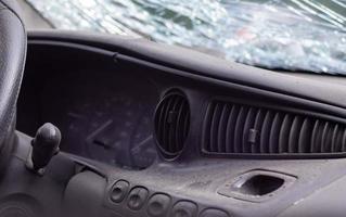 Close-up of the steering wheel of a car after an accident. The driver's airbags did not deploy. Soft focus. Broken windshield with steering wheel. Vehicle interior. Black dashboard and steering wheel. photo