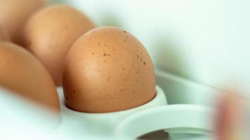 Raw chicken eggs in the refrigerator, close-up. Brown eggs in an egg rag on a shelf on the refrigerator door. selected focus. photo