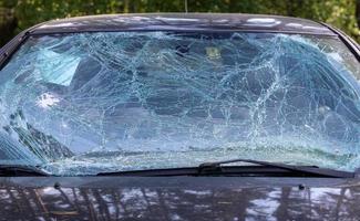 Close-up of a car with a broken windshield after a fatal crash. Consequence of a fatal car accident. Automobile danger. Reckless dangerous driving. Vehicle after an accident with a pedestrian. photo