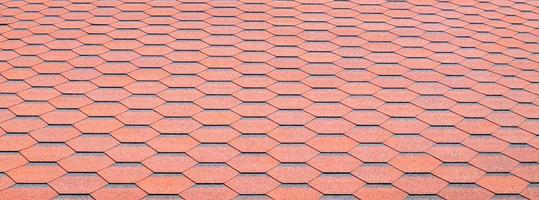 New roof with red shingles. Tiles on the roof of the house. Use to advertise roof fabrication and maintenance. Spotted texture. Affordable roofing. Banner with copy space. photo