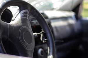 primer plano del volante de un coche después de un accidente. las bolsas de aire del conductor no se desplegaron. enfoque suave. parabrisas roto con volante. interior del vehiculo salpicadero y volante negros. foto