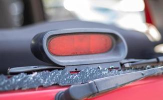 un automóvil después de un accidente con una ventana trasera rota. ventana rota en un vehículo con luz de freno trasera. restos interiores, vista detallada de primer plano de un coche moderno dañado. foto