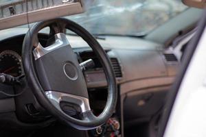 primer plano del volante de un coche después de un accidente. las bolsas de aire del conductor no se desplegaron. enfoque suave. parabrisas roto con volante. interior del vehiculo salpicadero y volante negros. foto