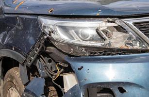 Broken headlights as a result of a collision. Broken blue car after an accident. Car accident concept. Damaged emergency headlight, hood and bumper. Damage to the car body after the accident. photo