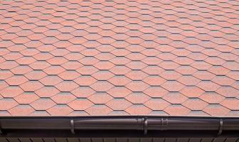 New roof with red shingles. Tiles on the roof of the house. Use to advertise roof fabrication and maintenance. Spotted texture. Affordable roofing. High quality photo with copy space.