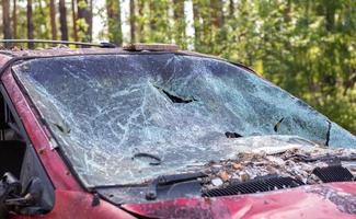 Close-up of a car with a broken windshield after a fatal crash. Consequence of a fatal car accident. Automobile danger. Reckless dangerous driving. Vehicle after an accident with a pedestrian. photo