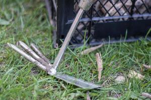 Garden tool rake chopper for gardening on the background of plastic boxes. The concept of gardening and sustainable summer. Metal garden tool with a rake and a hoe on a natural background. photo