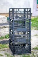 Plastic empty black boxes stacked together for plants or harvest. On a sunny day in early spring. Gardening concept. Household crop collection and storage boxes standing in the backyard. photo