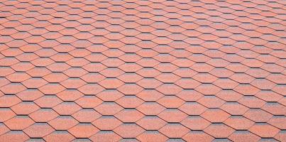 New roof with red shingles. Tiles on the roof of the house. Use to advertise roof fabrication and maintenance. Spotted texture. Affordable roofing. High quality photo with copy space.