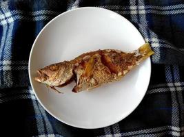 ikan goreng o pescado frito en un plato. comida culinaria tradicional indonesia foto