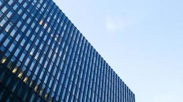 Modern high-rise building against the blue sky. Bottom view of a skyscraper in the business district. Low angle view of the glass facade of an office building. photo