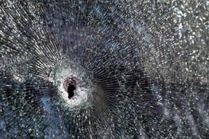 Holes on the windshield of the car, it was shot from a firearm. Bullet holes. Smash car windshield, broken and damaged car. The bullet made a cracked hole in the glass. photo