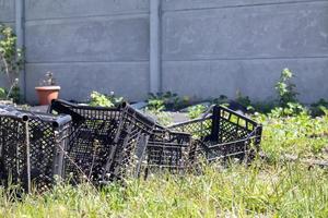 Plastic empty black boxes stacked together for plants or harvest. On a sunny day in early spring. Gardening concept. Household crop collection and storage boxes standing in the backyard. photo