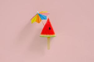 Red slice watermelon design as ice cream with stick that have cocktail umbrella photo