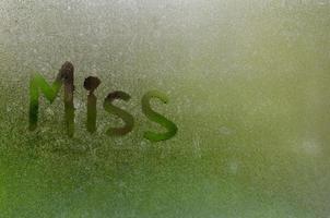 Word writing as Miss on window which fogged up after rain with blurred green color background photo