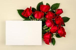 Red roses bouquet with blank white paper card on beige color background. photo