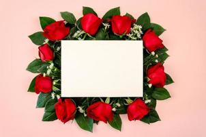 Red roses bouquet with blank white paper card on pastel pink background. photo