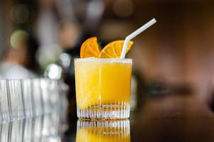A glass of orange cocktail puts on table of the bar for Holiday and summer drink concept. photo
