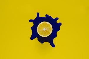 rebanada de limón en el color del cartel azul oscuro que cae sobre el fondo amarillo. foto