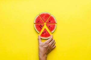 Hand taking a piece of watermelon that cut like pizza. photo