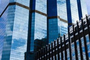 Blue sky and clouds reflected on the glass of office business buildings in the city center on a bright sunny day. photo