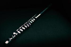 Transverse flute, a classic musical instrument on black background and natural light
