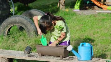 kleines mädchen mit hut hilft ihrer mutter im garten, einem kleinen gärtner. süßes mädchen, das blumen in töpfen zum verkauf pflanzt. kleiner Familienbetrieb video