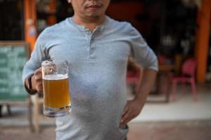 Young man holding a glass of beer and is it true that drinking beer makes you fat photo