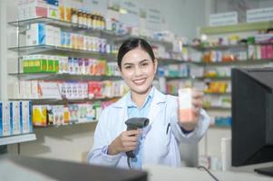 Farmacéutica femenina escaneando código de barras en una caja de medicamentos en una farmacia moderna. foto