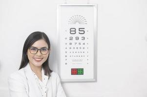 Young ophthalmologist doing visual test for customer using eye chart in optical center, eyecare concept. photo