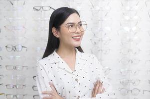 joven clienta eligiendo anteojos en el centro óptico, concepto de cuidado de la vista. foto