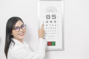 Young ophthalmologist doing visual test for customer using eye chart in optical center, eyecare concept. photo