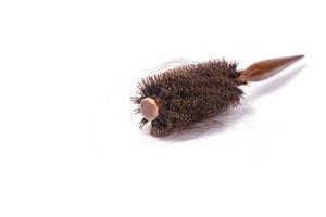 Cepillo de pelo redondo con cabello perdido sobre fondo blanco. foto