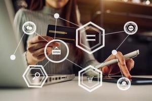 Close up of Hand using credit card and smartphone, laptop computer on wooden desk with VR icon chart graph diagram photo