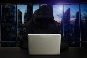 Hacker using computer with digital interface while sitting at desk of blurry interior. Hacking and thief concept. photo