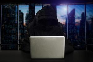 Hacker using computer with digital interface while sitting at desk of blurry interior. Hacking and thief concept. photo