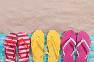 Sand copy space. Sand background top view. Multicolored beach flip flops photo