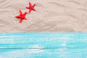 Summer concept - red starfish on the sand top view photo