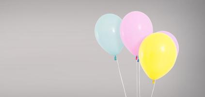 Globos de helio de colores aislados sobre fondo gris, concepto de cumpleaños foto