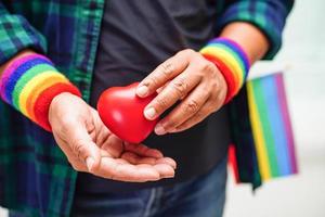 Asian woman holding red hert with rainbow flag, LGBT symbol rights and gender equality, LGBT Pride Month in June. photo