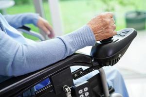 Asian elderly woman disability patient sitting on electric wheelchair in park, medical concept. photo